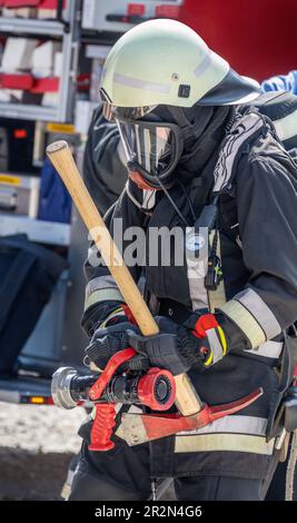 Feuerwehrmann in Aktion mit Gasmaske und Spitzhacke Stockfoto