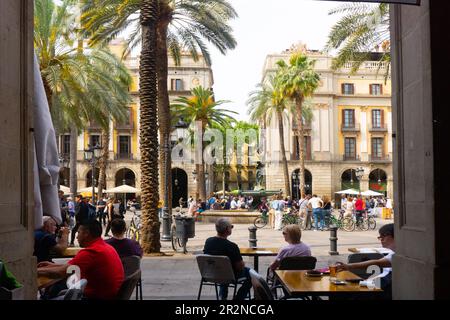 Restaurants und Cafés im Freien umgeben den Placa Reial, vor der Rambla, in Barcelona, Spanien. Beliebt bei Straßenmusikern und Touristen. Stockfoto