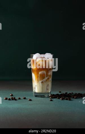 Schwarzer Kaffee mit Eis und Sahne in einem großen Glas. Kaffeebohnen. Stockfoto