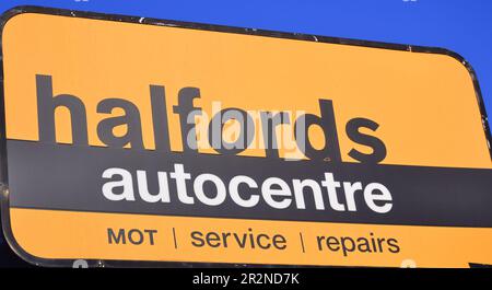 Schild: „Halfords autocenter“ mit TÜs, Wartung sowie Fahrzeug- und Fahrzeugreparaturen in Manchester, Großbritannien Stockfoto