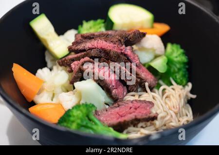 Gegrilltes Rindersteak und Sommergemüse in asiatischem Ramen-Nudelsuppe-Schüssel. Stockfoto