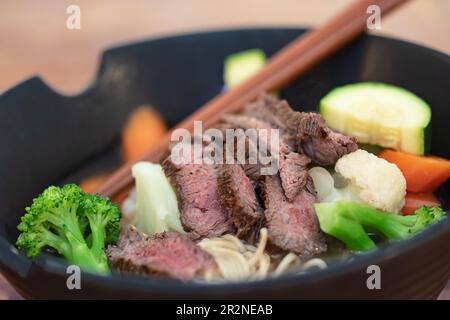 Gegrilltes Rindersteak und Sommergemüse in asiatischem Ramen-Nudelsuppe-Schüssel. Stockfoto