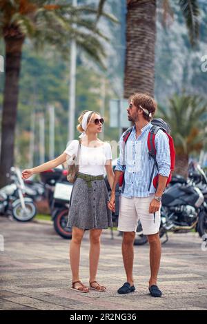 Ein Paar, das in der Sommerstadt Urlaub macht und Händchen hält. Sommerspaziergang in der Stadt. Touristen, Paare, Reisen, lustiges Konzept. Stockfoto