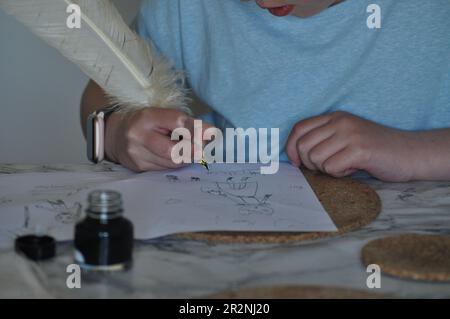 Ein Mädchen, das eine Federfeder und Tinte benutzt, um auf weißes Papier zu schreiben und zu zeichnen Stockfoto