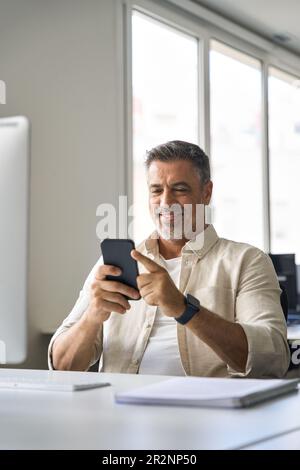Vertikales Porträt von mittelalterlichen hispanischen Unternehmen mit Handy-App. Stockfoto