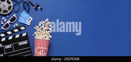 Flache Laiengestaltung mit Klappbrett, Kinokarten und Popcorn auf blauem Hintergrund, Platz für Text. Bannerdesign Stockfoto