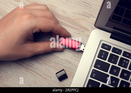 Mann, der ein usb-Flash-Laufwerk an einen Laptop am weißen Holztisch anschließt, Draufsicht Stockfoto