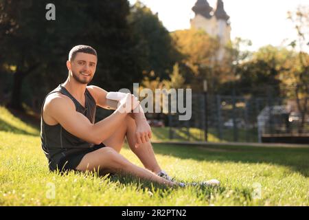 Der Mann kontrolliert den Blutdruck mit dem modernen Monitor nach dem Training im Park. Platz für Text Stockfoto