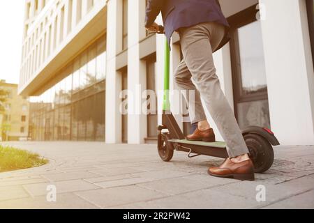 Geschäftsmann, der einen modernen Motorroller auf der City Street fährt, Nahaufnahme. Platz für Text Stockfoto