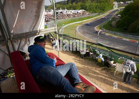 20. Mai 2023, Rheinland-Pfalz, Nürburg: Motorsportfan Tobias liegt während des 24-stündigen Rennens auf dem Nürburgring im Abschnitt „Brünnchen“ auf seiner Couch, die er auf einem hohen Sitz montiert hat. Foto: Thomas Frey/dpa Credit: dpa Picture Alliance/Alamy Live News Stockfoto