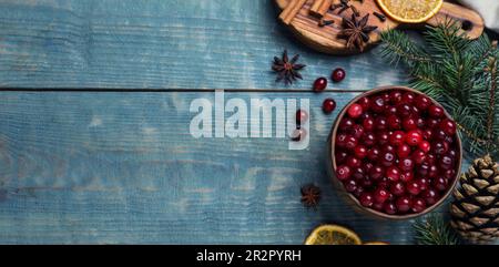 Flache Laienzusammensetzung mit frischen reifen Cranberrys auf blauem Holztisch, Platz für Text. Bannerdesign Stockfoto