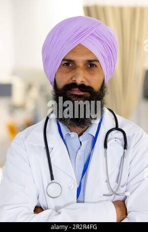 Portrait des glücklichen sikh männlichen Arztes, der Turban und Stethoskop trägt, lächelnd im Krankenhaus Stockfoto
