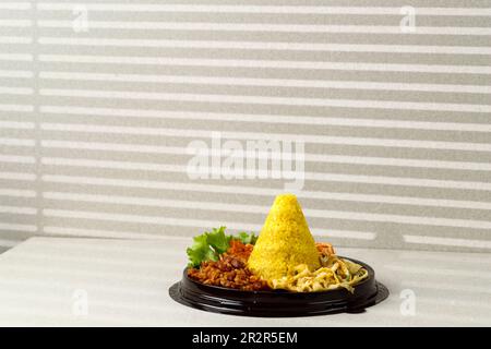 Tumpeng Mini Nasi Kuning oder kleiner konischer gelber Reis, indonesische festliche Speisen für Indoneia Unabhängigkeitstag 17 Agustus Stockfoto