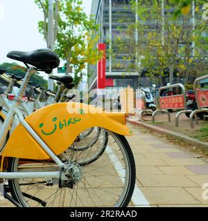 YouBike Smile Bikes auf einem Gehweg in Kaohsiung City im Süden Taiwans; gelbes Lächeln für ortsansässige Pendler und Touristen. Stockfoto