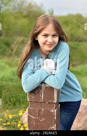 Hübsches junges Mädchen mit langen Haaren in kausalen Klamotten, das draußen posiert Stockfoto