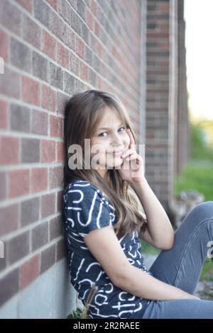 Hübsches, blondes Mädchen, das draußen mit einem Lächeln und Selbstvertrauen posiert Stockfoto