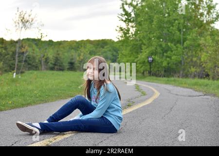 Hübsches, blondes Mädchen, das draußen mit einem Lächeln und Selbstvertrauen posiert Stockfoto