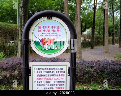 Zweisprachiges Schild auf Englisch und Chinesisch, in dem die Besitzer aufgefordert werden, ihren Hund an der Leine zu halten und hinter ihm zu putzen; Daan Park Taipei, Taiwan; aufsaugen und an der Leine halten. Stockfoto