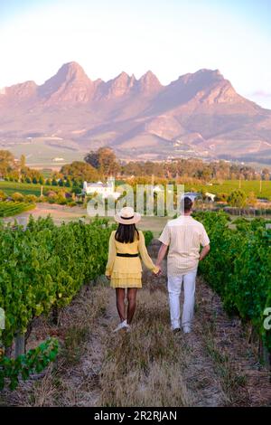 Ein paar Männer und Frauen machen Urlaub in Südafrika in einer Weinbergslandschaft mit Bergen in Stellenbosch, nahe Kapstadt, Südafrika Stockfoto