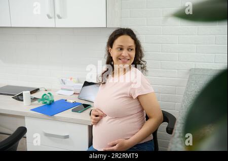 Schwangerschaft 3D. Trimenon. Charmante schwangere Frau besucht eine Ärztin für eine regelmäßige ärztliche Untersuchung. Stockfoto