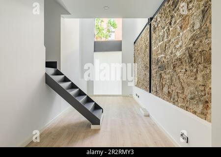 Mischung aus neuer und alter Architektur. Renoviertes Apartment mit restaurierter alter Mauer links von alten Stadtgebäuden. Inneneinrichtung eines leeren renovierten Zimmers mit Stockfoto