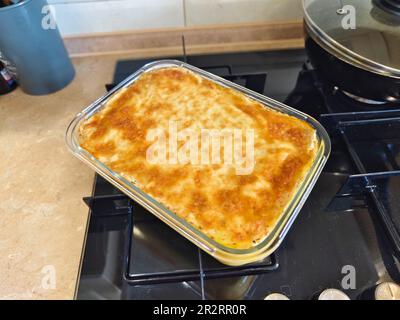 Herzhafte Kartoffelgratin mit Parmesan-Käsesahne und köstlichem Räucherspeck, frisch aus dem Ofen auf einem Holztisch serviert Stockfoto