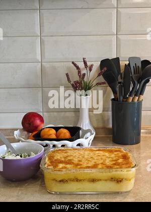 Herzhafte Kartoffelgratin mit Parmesan-Käsesahne und köstlichem Räucherspeck, frisch aus dem Ofen auf einem Holztisch serviert Stockfoto