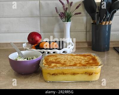 Herzhafte Kartoffelgratin mit Parmesan-Käsesahne und köstlichem Räucherspeck, frisch aus dem Ofen auf einem Holztisch serviert Stockfoto