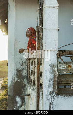 Afrikanische Frau schaut von einem alten Balkon in Accra Ghana Westafrika Stockfoto