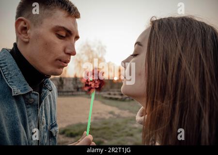 Junger Mann und Frau, die auf ein Windspielzeug blasen, Ökologie-Konzept Stockfoto