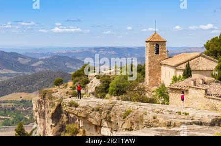 Menschen auf den Klippen genießen den Blick über die Berge und die Kirche in Siurana, Spanien Stockfoto
