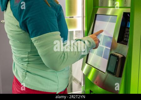 Eine junge Frau kauft eine Fahrkarte für öffentliche Verkehrsmittel in einem Automaten, im Stadt- und Ballungsverkehr Stockfoto