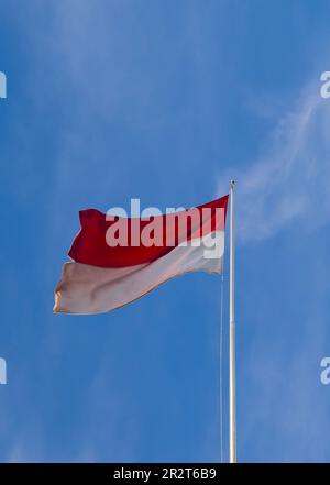 Die rote und weiße Fahnenstange flattert gegen den Himmel, die indonesische Flagge auf dem Pol gegen den Himmel Stockfoto