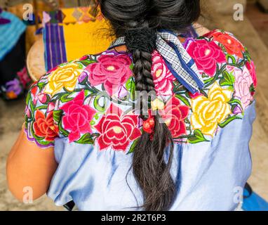 Traditioneller Look einer einheimischen Mexikanerin mit geflochtenem Haar und blauem Hemd mit bunten Blumen Stockfoto