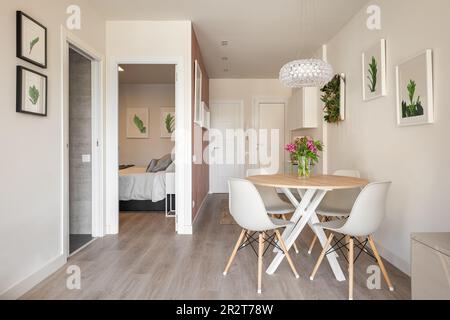 Stilvoller Essbereich im Wohnzimmer des Studios mit Tisch und Stühlen und dekorativen Accessoires mit Blick auf das Außenbad und das Schlafzimmer. Konzept von Stockfoto