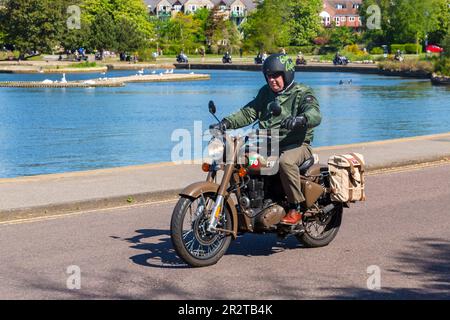 Poole, Dorset, Großbritannien. 21. Mai 2023 Bournemouth and Poole Distinguished Gentlemen’s Ride ist eine von vielen weltweit jährlich stattfindende Veranstaltung, um Geld und Bewusstsein für die Gesundheit von Männern zu schaffen. Im Rahmen der Fahrt fahren Hunderte von Motorrädern, viele davon im Vintage-Stil, durch den Poole Park auf dem Weg nach Bournemouth mit vielen ihrer Fahrer, die angemessen gekleidet sind, in Krawatten im Retro-Stil, Schnurrbart und Tweeds an einem schönen sonnigen Tag. Mann, der mit dem Royal Enfield Motorrad fährt. Quelle: Carolyn Jenkins/Alamy Live News Stockfoto