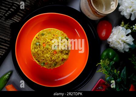 Schüssel mit Instantnudeln mit Gemüse auf dunklem Hintergrund Stockfoto