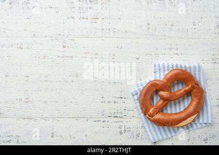 Oktoberfest-Konzeptkarte. Traditionelle bayerische Brezeln mit Bierfläschchen auf altweißem rustikalem Hintergrund. Perfekt für das Oktoberfest. Oktoberfest-Essen Stockfoto