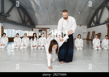 Aikido-Ausbilder, der Teenager-Kämpfer beim Gruppentraining im Fitnessstudio unterrichtet Stockfoto