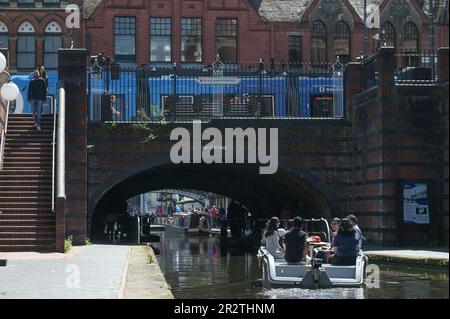 Brindleyplace, Birmingham, 21. Mai 2023 - Besucher des Stadtzentrums von Birmingham genossen Temperaturen von bis zu 21 Grad Celsius, während sich das Wetter zu sommerlicheren Bedingungen zu wenden beginnt. Die Leute genossen Bootstouren auf den Kanälen und benutzten Liegestühle, um sich in Brindleyplace zu sonnen. Kajakfahrer wurden auch auf den Kanälen gesehen, während andere vom Kanal aus zuschauten. Kredit: Stop Press Media / Alamy Live News Stockfoto