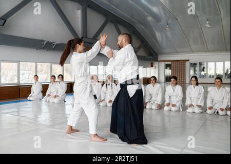 Sensei mit einer jungen Studentin, die Aikido-Technik demonstriert Stockfoto