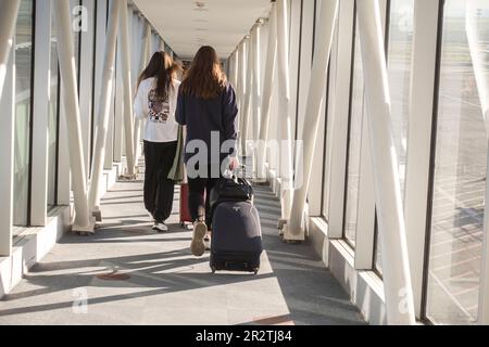 Rückansicht der Passagiere, die mit rollendem Gepäck durch den Korridor laufen, der mit dem Flugzeug Board Tiflis Airport, TBS, Tiflis, Georgia verbunden ist Stockfoto