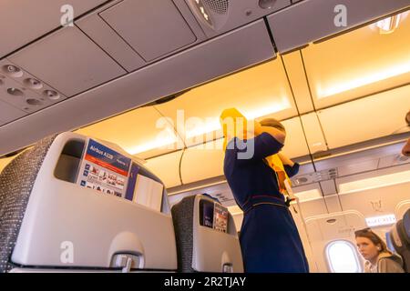 Ein Flugbegleiter, der Passagieren in einem Airbus A320-Flugzeug von Fly Arna eine Schwimmweste vorführt Stockfoto