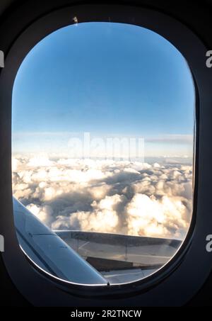 Wolken durch den Düsentriebwerk - Luftaufnahme von einem Fenstersitz im Flugzeug Stockfoto
