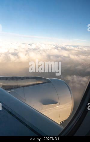 Wolken durch den Düsentriebwerk - Luftaufnahme von einem Fenstersitz im Flugzeug Stockfoto