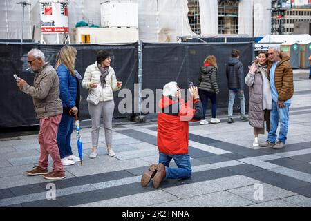 Ein kniender Mann fotografiert ein älteres Paar vor dem Dom in Köln. Ein kniender Mann fotografiert ein aelteres Paar vor de Stockfoto