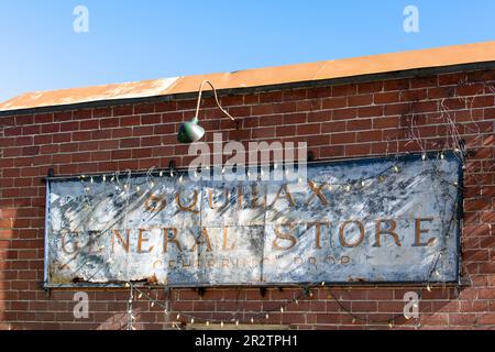 Chase, BC, Kanada; August 2022; Nahaufnahme des verwitterten Schilds des Squilax General Store an der Ziegelfassade des Gebäudes Stockfoto