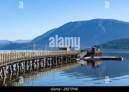 Salmon Arm, BC, Kanada; August 2022; Blick auf das Ende der geschwungenen Anlegestelle und Pier (Salmon Arm Wharf) mit Promenade am Ufer des Shuswap Lake und Panoramablick Stockfoto