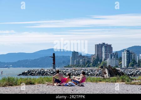 Vancouver, BC, Kanada-August 2022; Nahaufnahme einiger junger Menschen am Ambleside Beach in West Vancouver und Squamish Nation Welcome Figure in Backg Stockfoto