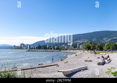 Vancouver, BC, Kanada-August 2022; Panoramablick über den Ambleside Beach in West Vancouver mit Menschen am Strand und Squamish Nation Willkommen Figur i. Stockfoto